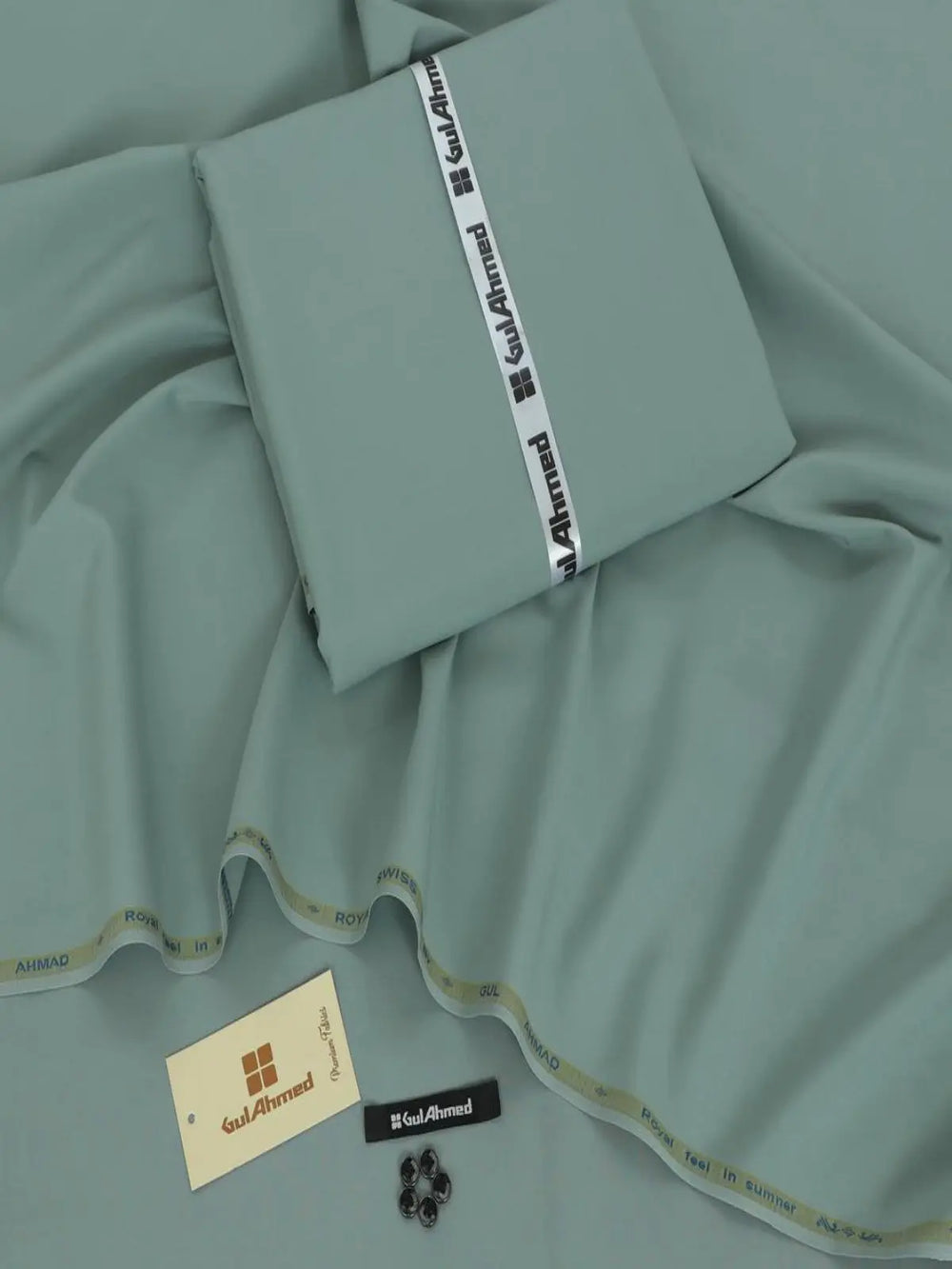 Light green men's wash wear suit fabric with label, buttons, and tag displayed on fabric