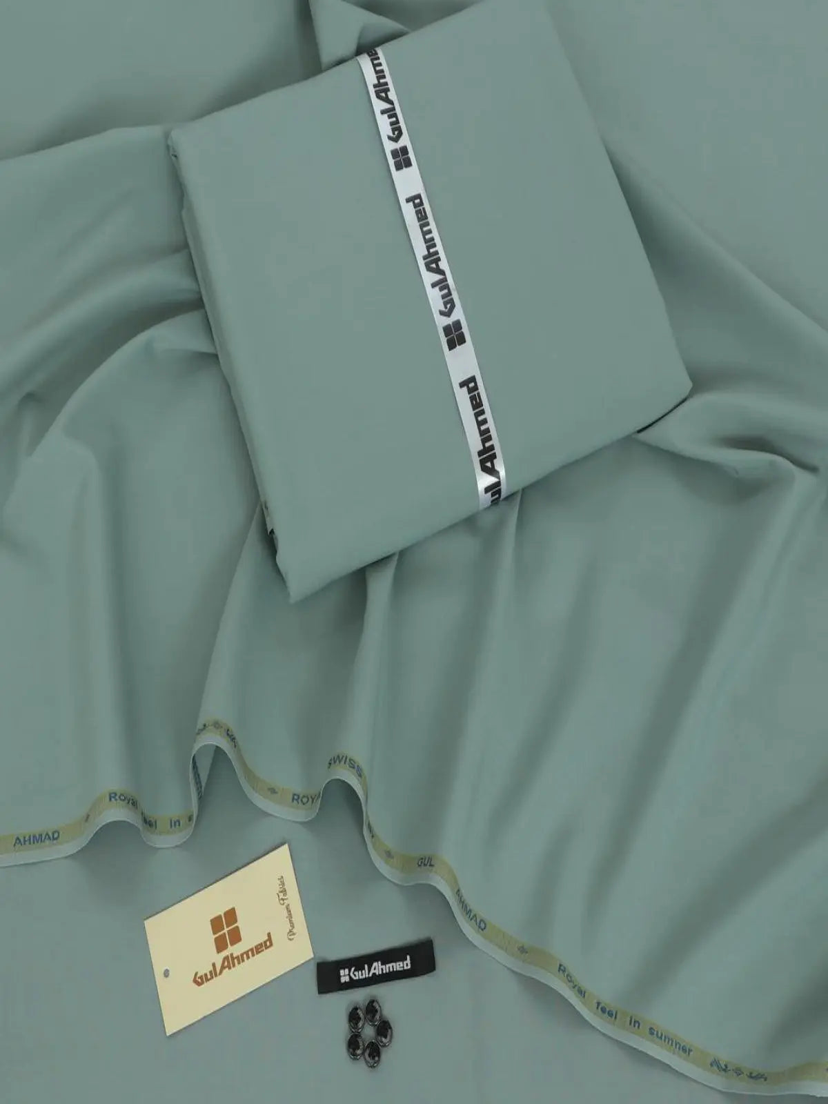 Light green men's wash wear suit fabric with label, buttons, and tag displayed on fabric