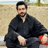 Man sitting on bench outdoors wearing traditional dark outfit, casual mens fashion