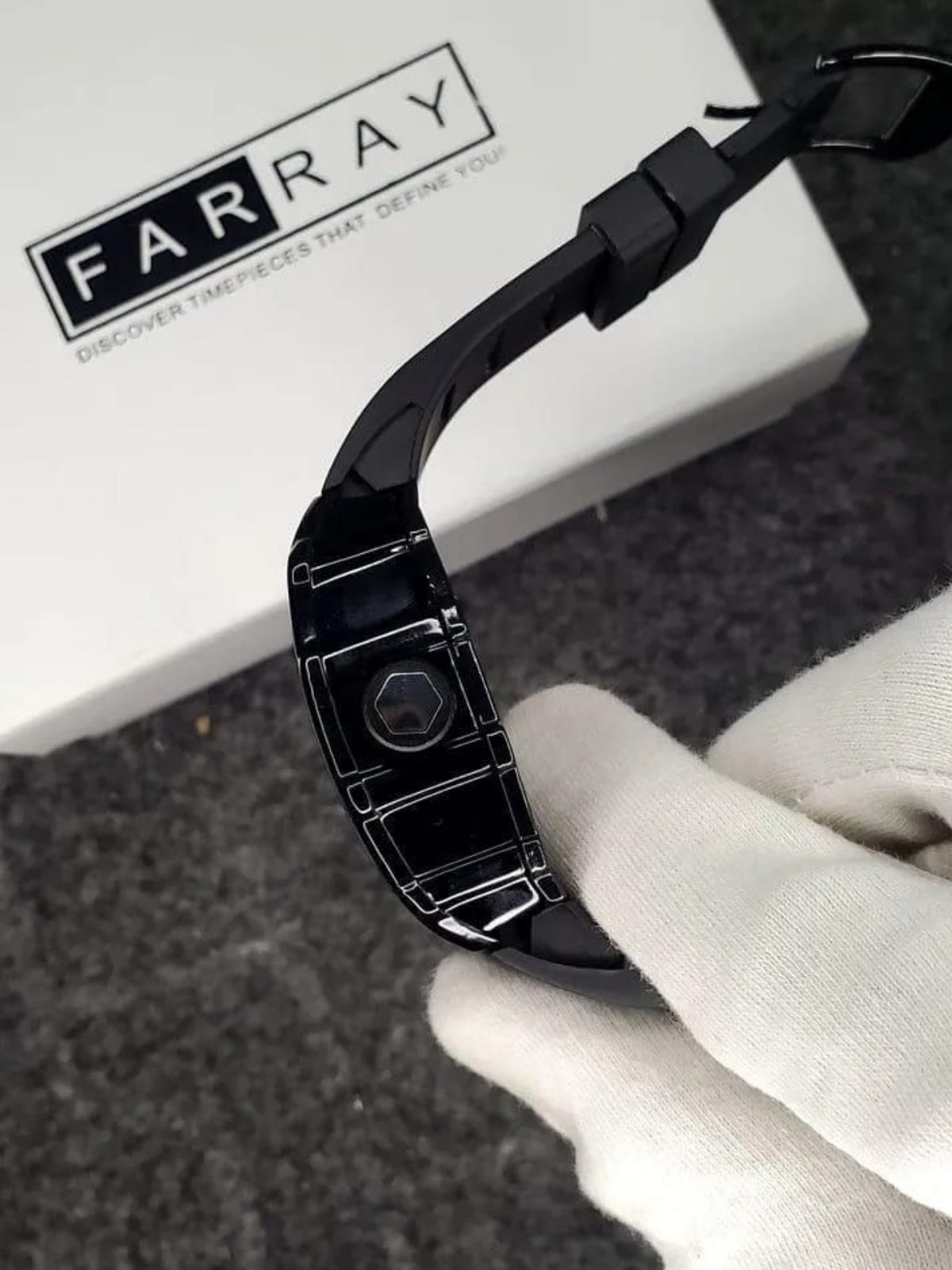 Black metal bracelet held by a gloved hand with 'FARRAY' branding in the background.