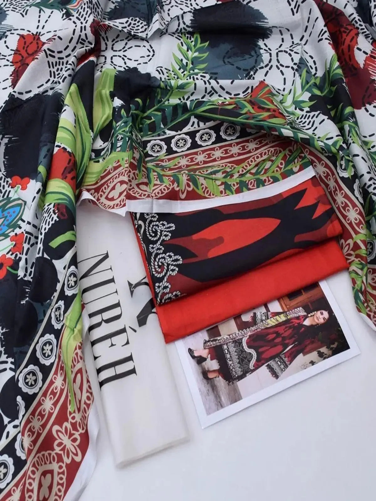 Red printed lawn 3-piece women’s suit with floral and geometric patterns, folded on a flat surface with a design card showing the outfit.