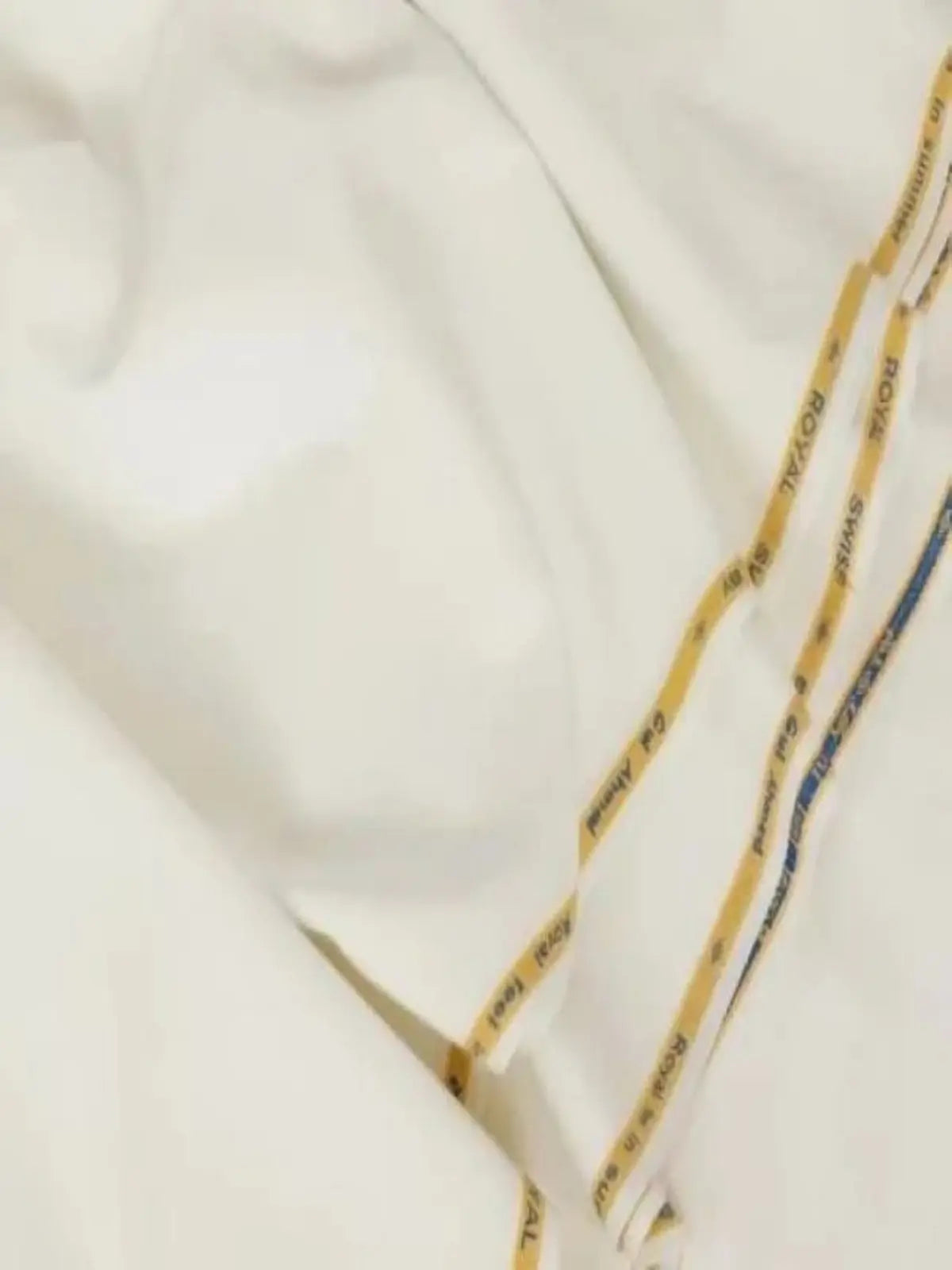 Off white unstitched men's suit fabric with yellow selvage detail, laid flat.