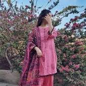 Woman in pink printed traditional outfit standing outdoors near blooming flowers